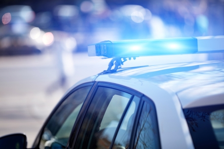 Close-up of a police car roof with flashing blue lights in daylight. | Orr Law Firm